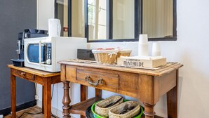 Una kitchenette con microondas, cafetera y cestas de mimbre sobre una mesa de madera.