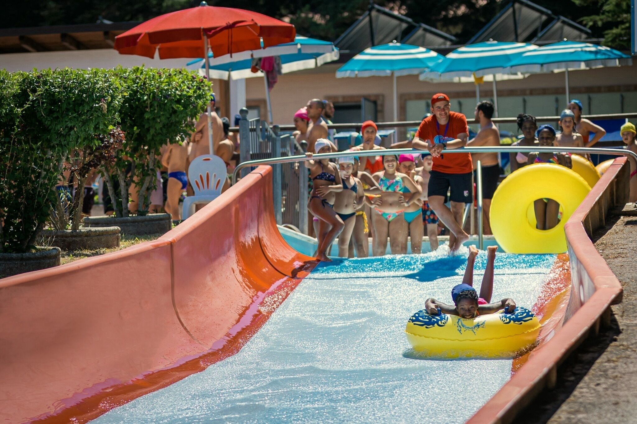 A water slide at a poolside area with spectators.