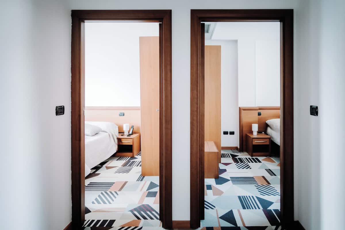 A hotel room with a bed, bedside tables, and a patterned floor.