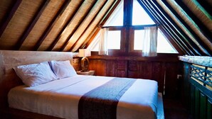 A bedroom with a wooden ceiling, a bed with white linens, a nightstand with a lamp, and a window with curtains. - 2-Mezzanine bedroom villa in Bali (Bali)