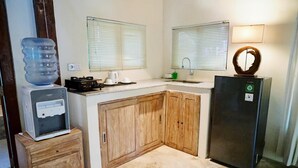 A compact kitchen with wooden cabinets, a refrigerator, a water dispenser, and a coffee maker. - 2-Mezzanine bedroom villa in Bali (Bali)