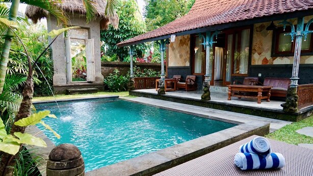 A pool area with a thatched-roof structure, lounge chairs, and a stone barrel. - 2-Mezzanine bedroom villa in Bali (Bali)