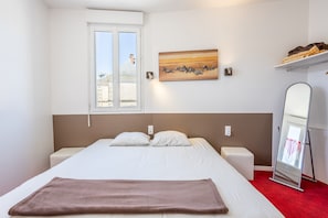 A bedroom with a bed, a window, a painting, a mirror, and a shelf with towels. - Room 'N°01' with Wi-Fi (Chantonnay)