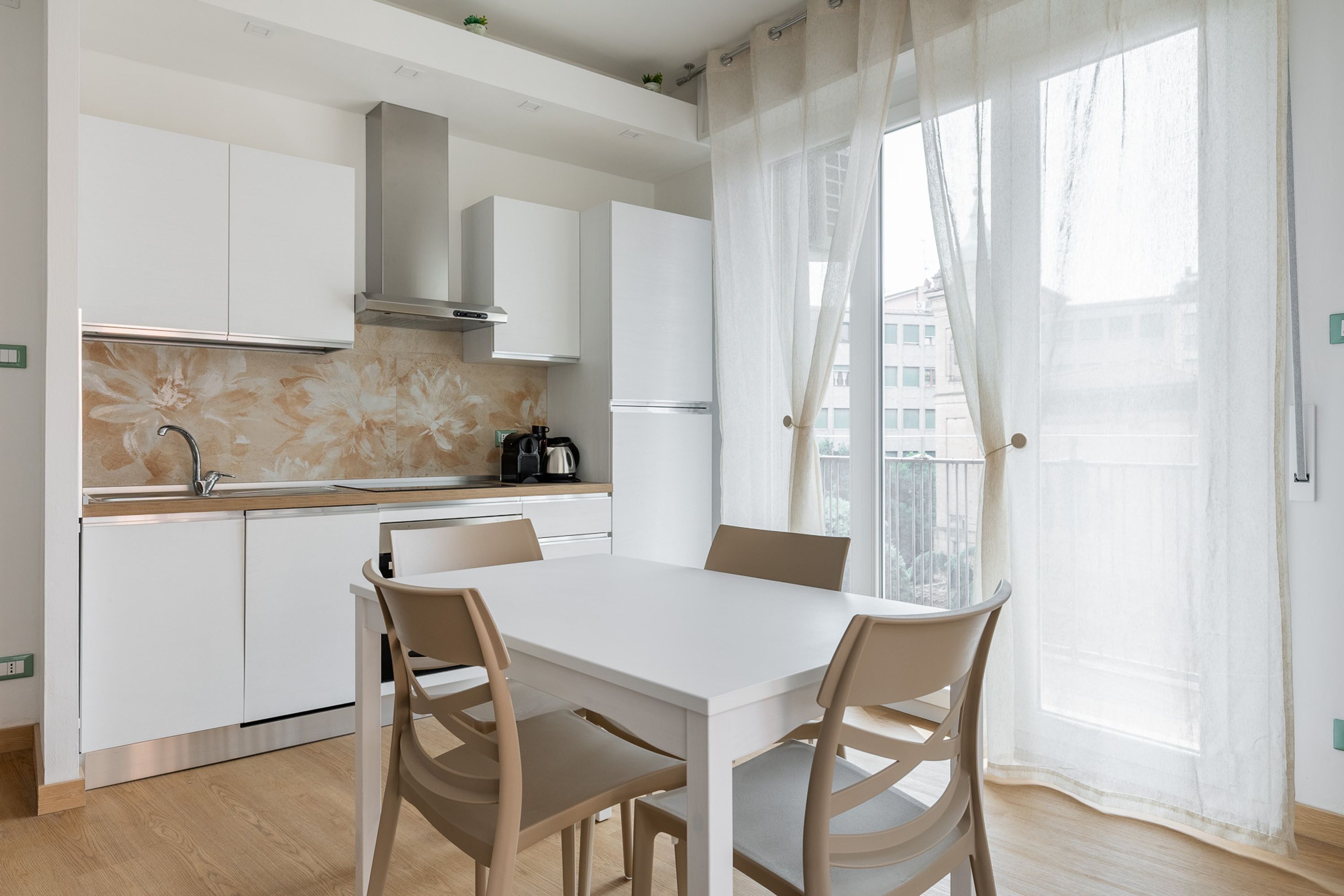 A modern kitchen with white cabinets, a white countertop, and a dining table with chairs.
