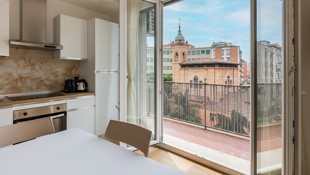 A modern kitchen with a large sliding glass door leading to a balcony with a city view. - Bologna City Center View by Wonderful Italy (Bologna)