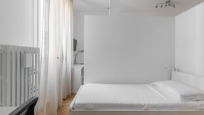 A minimalist bedroom with a bed, a desk, and a chair. - Bologna City Center View by Wonderful Italy (Bologna)