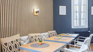 Une pièce moderne avec un mur lambré en bois, un banc blanc rembourré, une table avec une plante et une fenêtre donnant sur un beau paysage.
