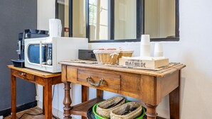 Una kitchenette equipada con microondas, cafetera y cestas de mimbre.