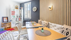 A modern living room with a sofa, dining table, and bookshelves. - Standard Room 'N°11' with Wi-Fi (Chantonnay)