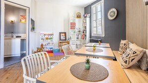 A dining area with a wooden table, white chairs, and a bookshelf filled with books and decorative items. - Standard Room 'N°11' with Wi-Fi (Chantonnay)