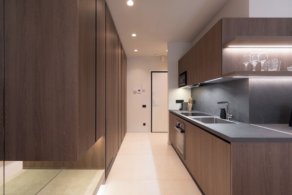 Une cuisine moderne avec des meubles en bois, un évier en acier inoxydable et un four à micro-ondes.