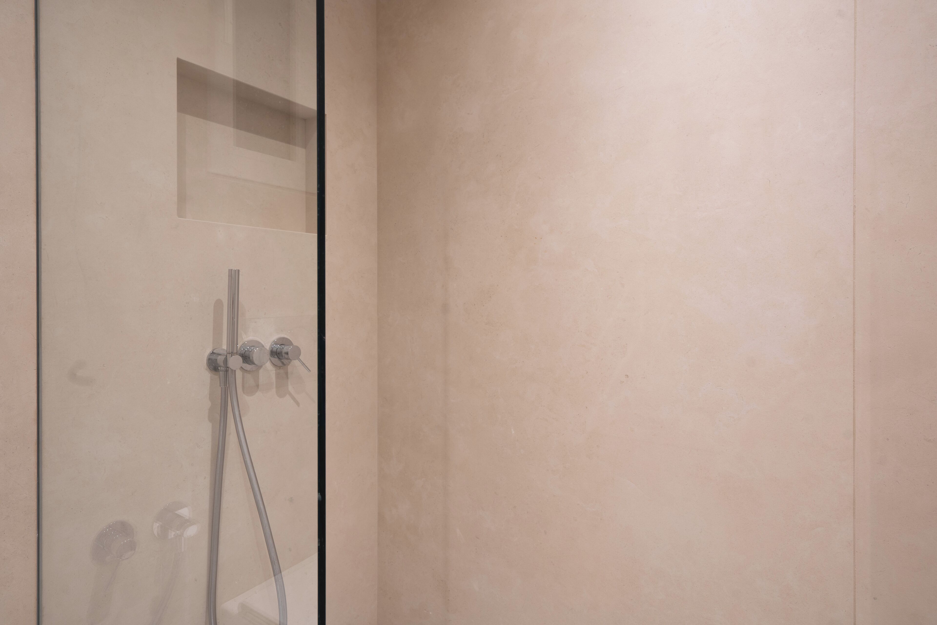 A shower area with a glass door, a towel rack, and a small shelf.