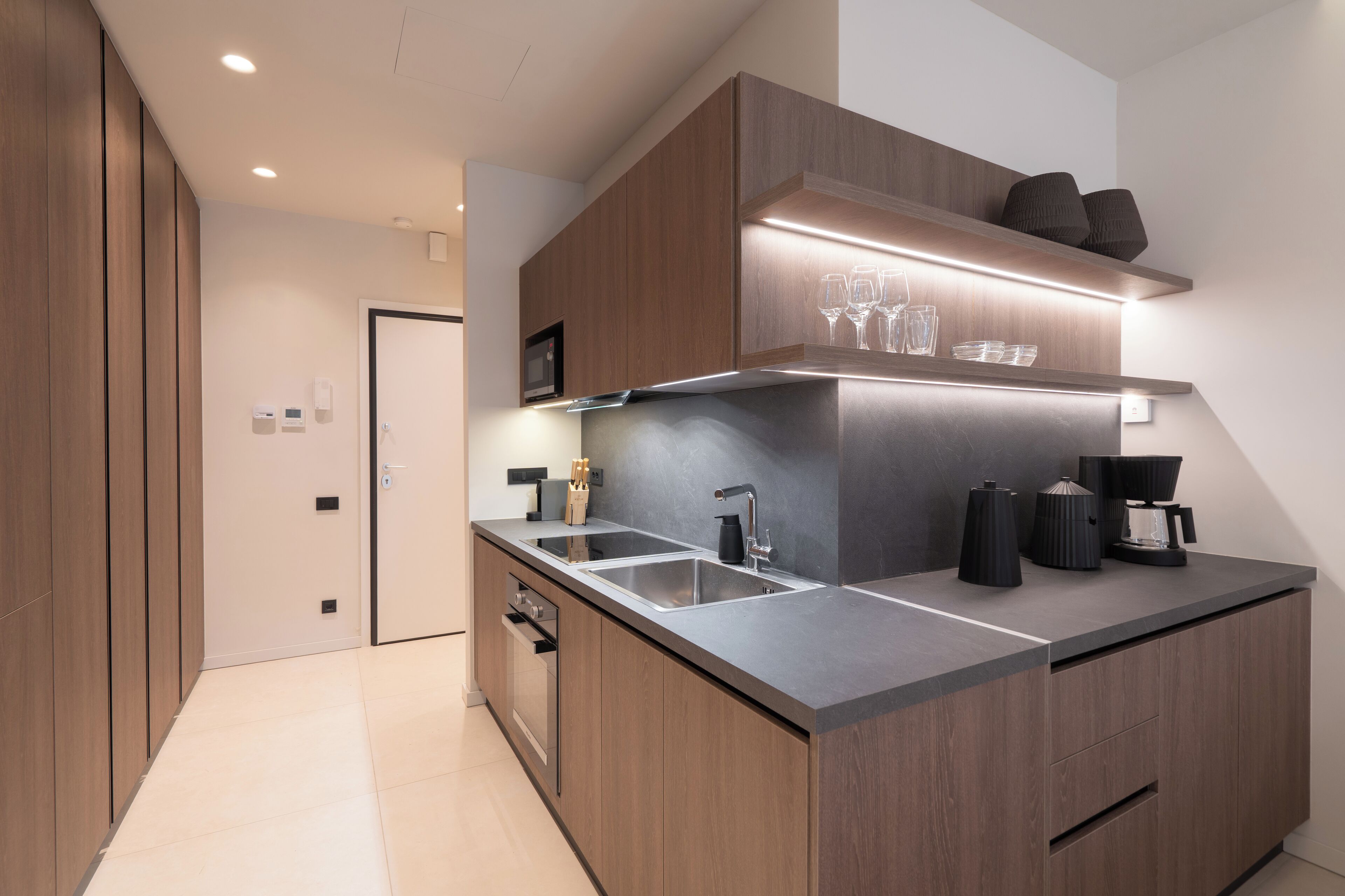 Una cocina moderna con armarios de madera, un lavamanos de acero inoxidable y una cafetera.