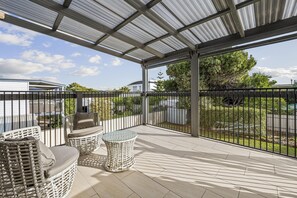 A covered patio with wicker furniture and a view of the surrounding area.