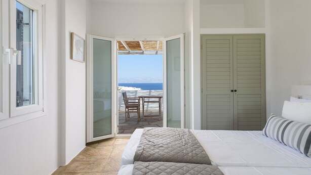 A bedroom with a bed, a green wardrobe, and a view of the sea. - Phaedrus Living: Paros Cycladic Residences 5 (Paros)