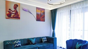 Una sala de estar moderna con un sofá azul, una mesa de centro con fruta y obras de arte en las paredes.
