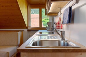 A kitchen with a stainless steel sink, wooden countertop, and a window with a view of a brick building.