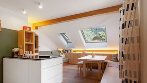 A modern kitchen with a central island, wooden beams, skylights, and a view of greenery.