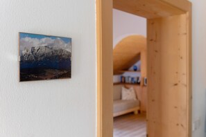 A room with a wooden door leading to another space, a framed picture on the wall, and a bed with a curved headboard. - Apartment 'Rielingerhof' with Mountain View, Shared Terrace and Wi-Fi (Klobenstein)