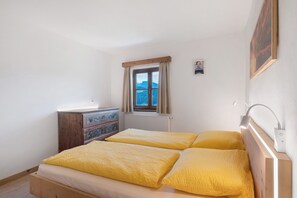 Een slaapkamer met een houten bed, een dressoir, een raam met uitzicht en een schilderij aan de muur.