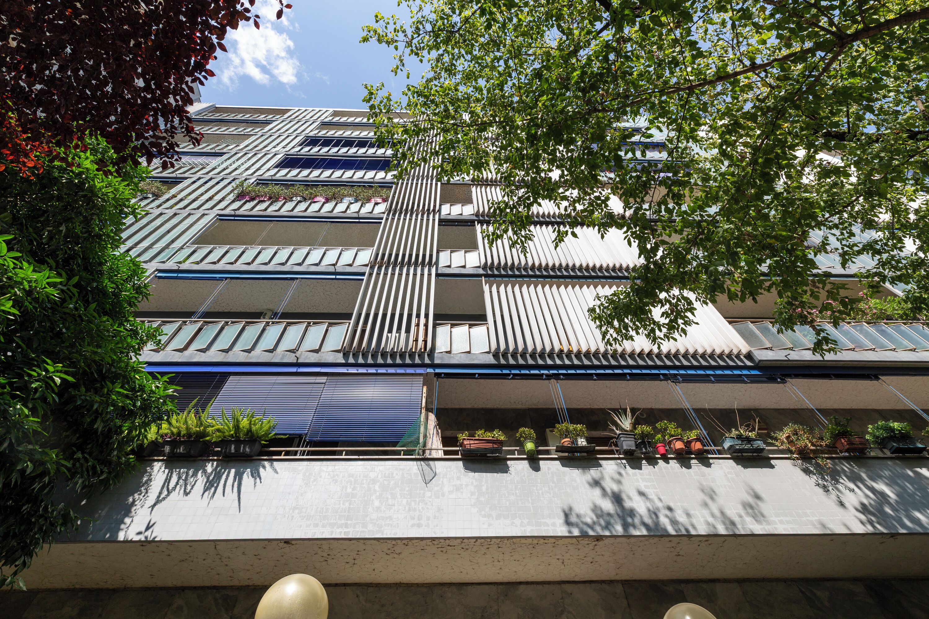 A modern building with multiple floors, large windows, and balconies.