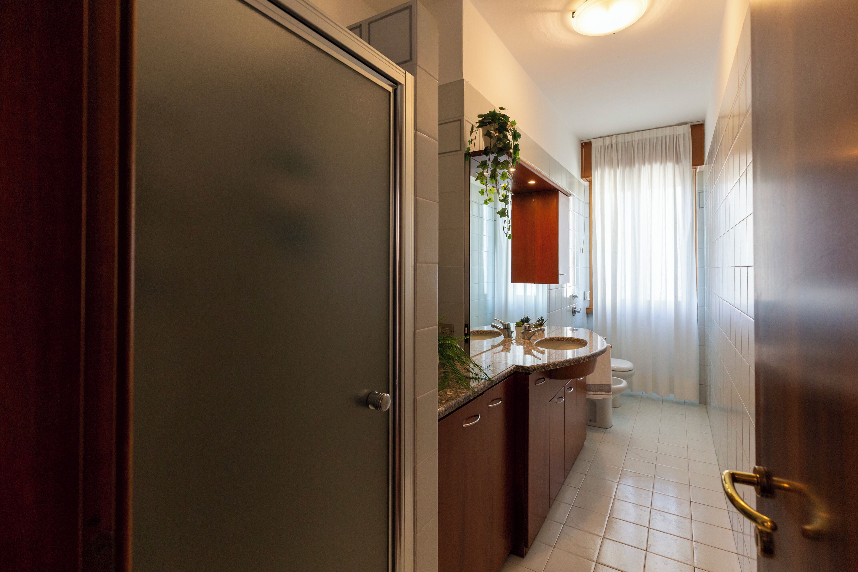 A bathroom with a wooden door, a sink, a toilet, and a mirror.