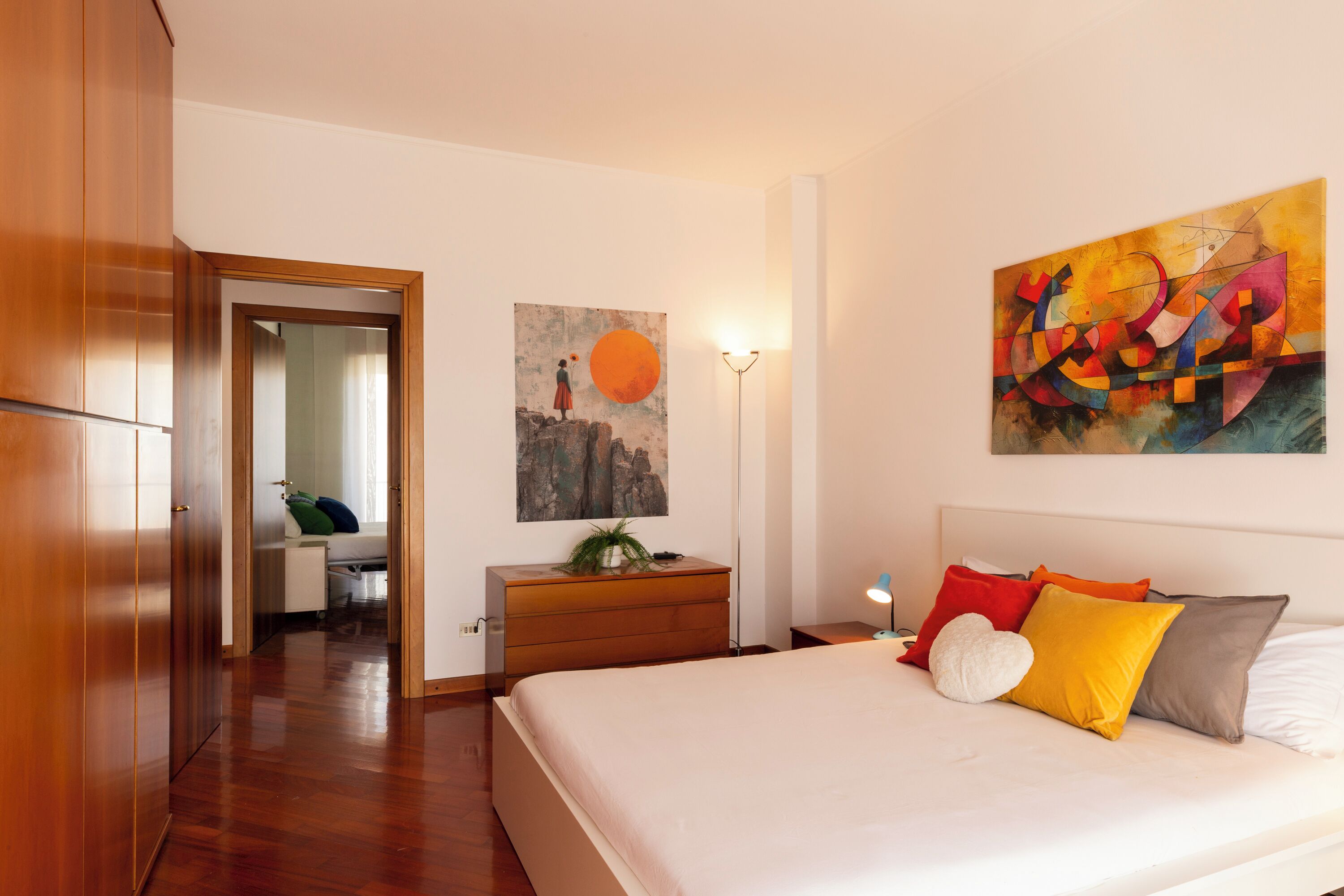 Une chambre à coucher avec un grand lit, une commode, une table de chevet et un tableau accroché au mur.