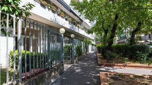 A narrow pathway flanked by a metal fence and a row of potted plants on the building's balcony. - notaMi - Simply Six (Milan)