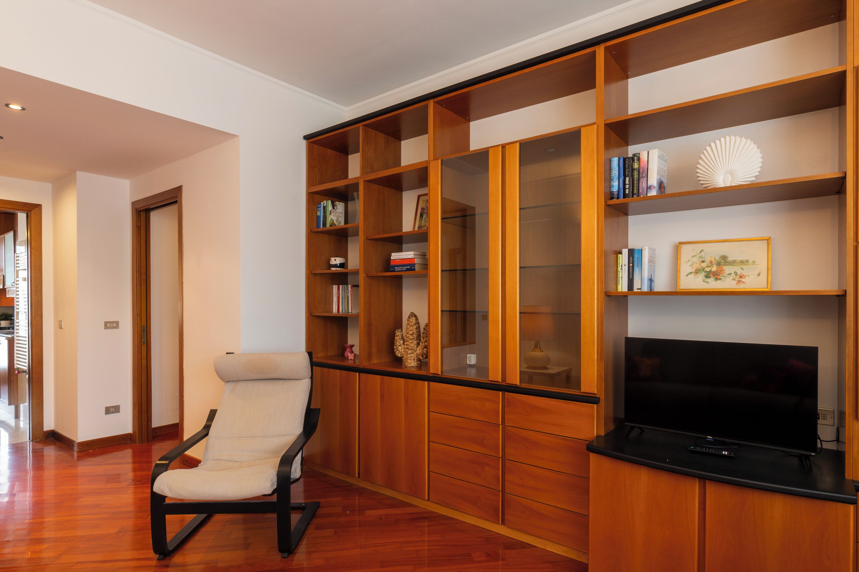 Una sala de estar con un mueble de madera para entretenimiento, un sofá y un televisor de pantalla plana.