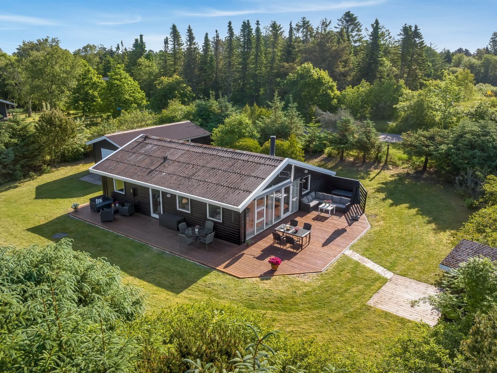 Ein modernes Haus mit Terrasse, Patio und großem Rasen.