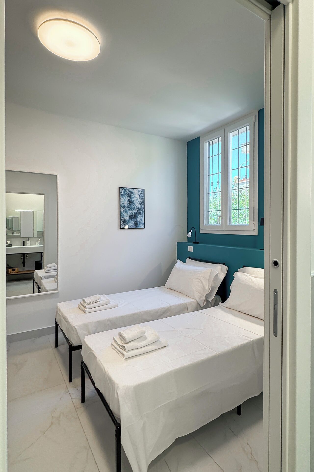 Ein Schlafzimmer mit zwei Betten, ein Badezimmer mit Spiegel und ein Fenster mit Blick.