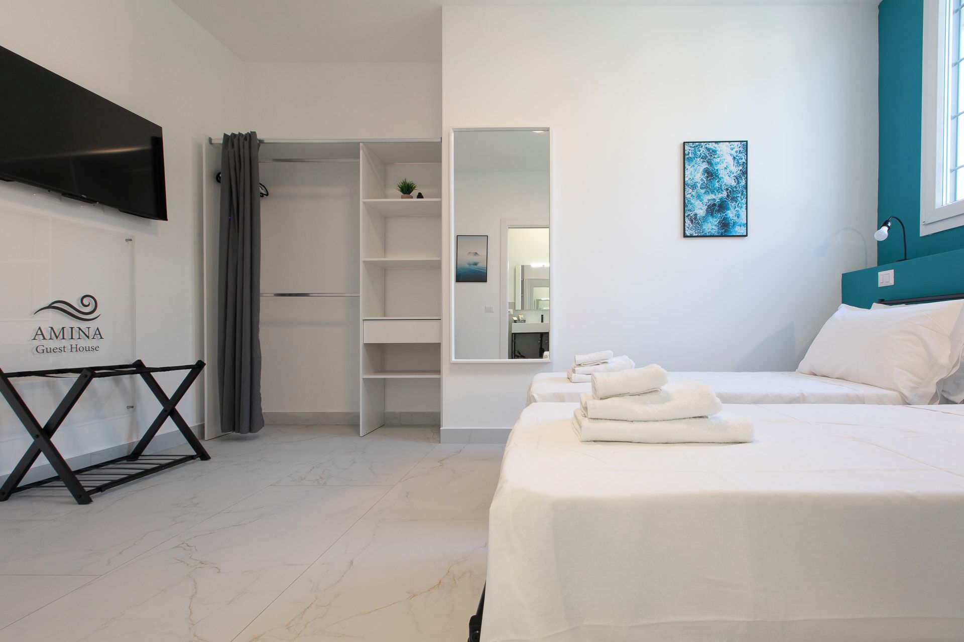 Een moderne hotelkamer met een bed, een garderobe, een spiegel en een aan de muur bevestigde televisie.