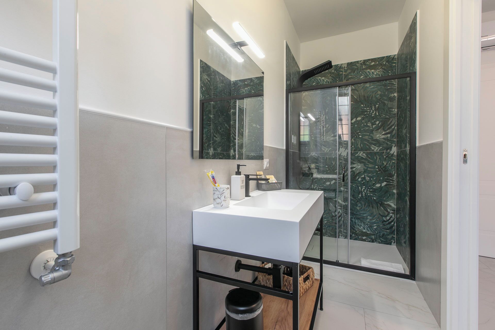 A modern bathroom with a white sink, a large mirror, and a glass shower enclosure.