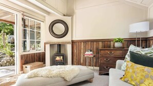 A cozy living room with a fireplace, a sofa, a coffee table, and a dresser.