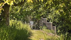 A wooden gate in a lush, green garden with a path leading through it.