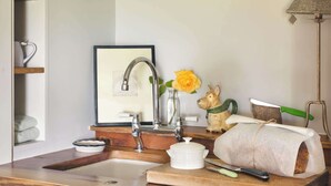 A kitchen counter with a sink, a framed picture, a vase with a yellow flower, and a dog figurine.