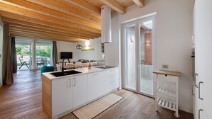 A modern kitchen with wooden beams, a central island, and a sliding glass door leading to an outdoor area.
