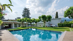 A swimming pool with a clear blue water surface, surrounded by a well-maintained lawn and trees.