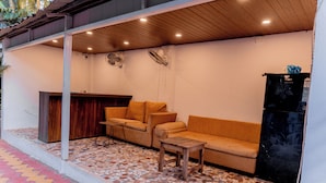 Une pièce avec un plafond en bois, un sol carrelé, un canapé, une petite table et un réfrigérateur.
