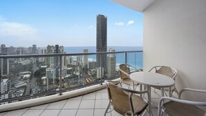 A balcony with a city view, a table, and two chairs.