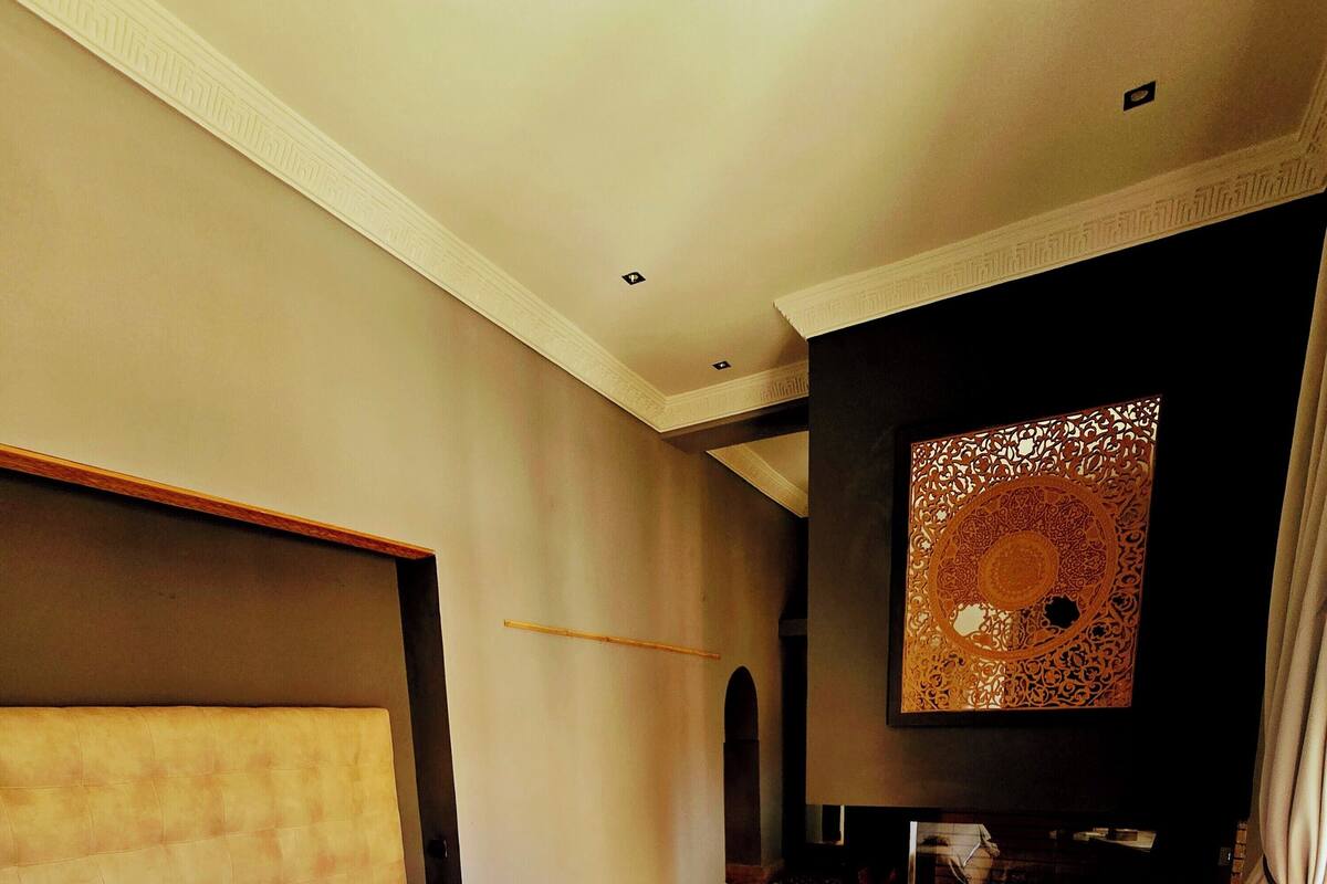 A hotel room with a large bed, a sofa, a TV, and a patterned rug.