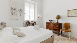 Un dormitorio con cama, cómoda, silla, escritorio y ventana.
