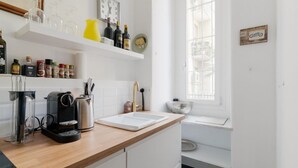 Una cocina con cafetera, copas de vino y un reloj.