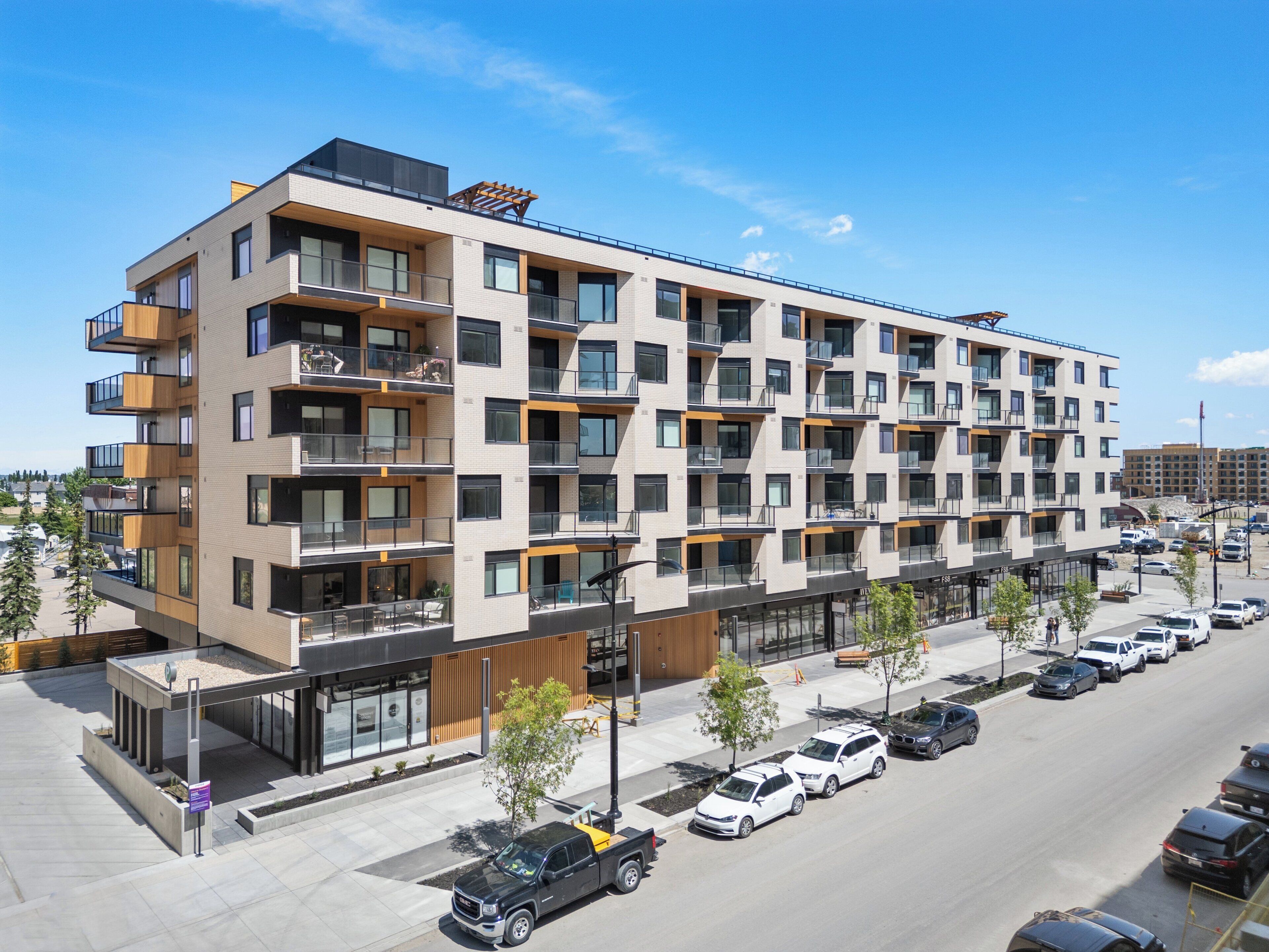 A multi-story residential building with balconies, a parking lot, and a street view.