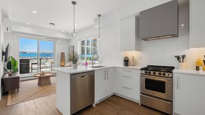 Une cuisine moderne équipée d’un lave-vaisselle, d’une cuisinière et de meubles blancs.