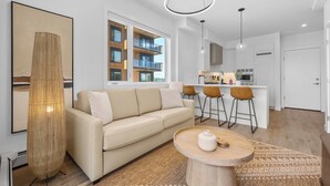 Un salon moderne avec un canapé beige, une table basse ronde en bois et un grand tableau abstrait.