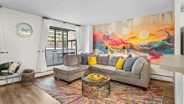 A modern living room with a large sectional sofa, a coffee table, a colorful rug, a wall clock, and a large abstract painting. - Mural Oasis w Sunroom, Parking, near Stampede (Calgary)