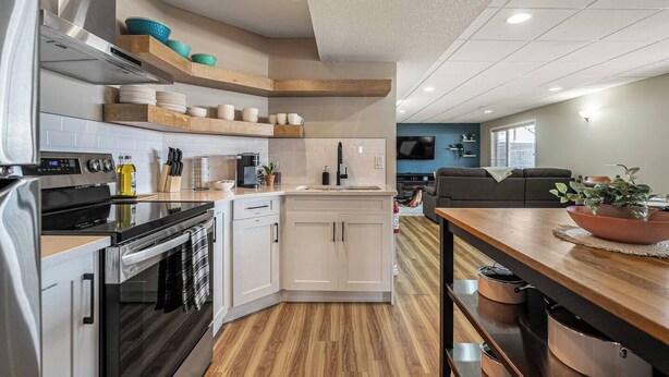 Una cocina moderna con armarios blancos, horno empotrado y una mesa de comedor de madera.