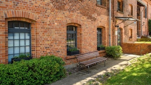 A brick building with arched windows, a bench, and potted plants. - Hotel Stadtgut (Berlin)