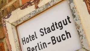 A sign with the text "Hotel Stadtgut Berlin-Buch" in a weathered frame. - Hotel Stadtgut (Berlin)